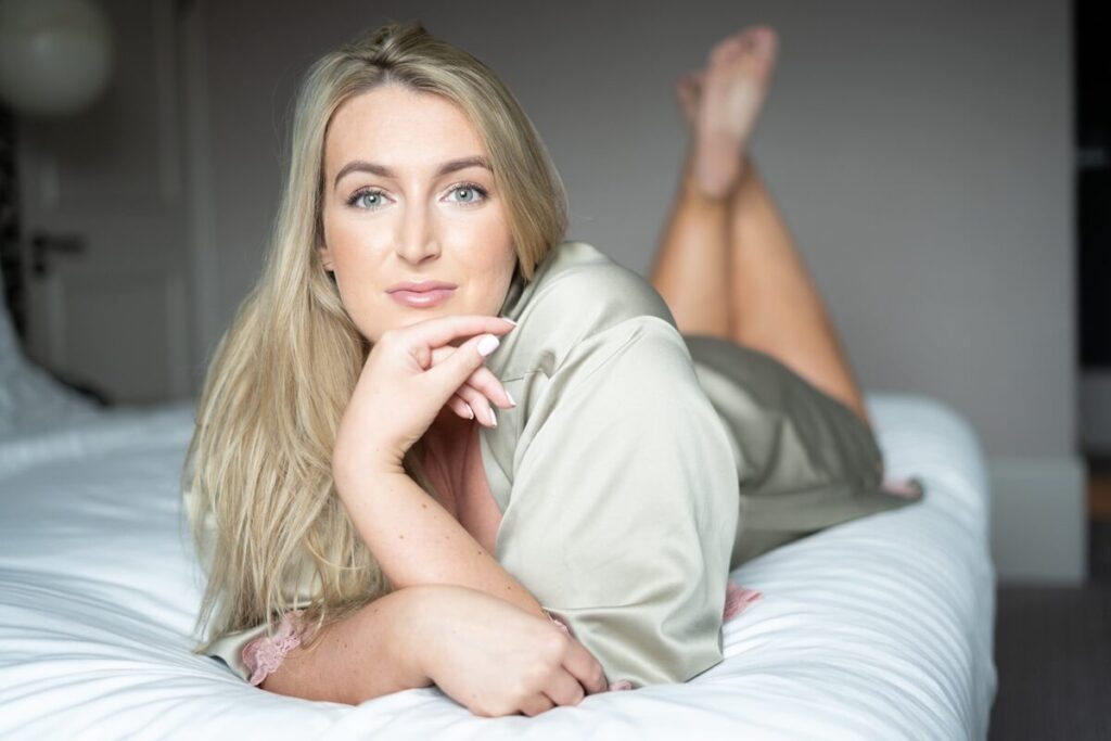 Cropped view of female model poses in bed, being lazy, being unable to wake  up, rolles on bedclothes. Adorable young woman enjoys early hours at bedroom.  Beauty, health and lifestyle conecpt Stock